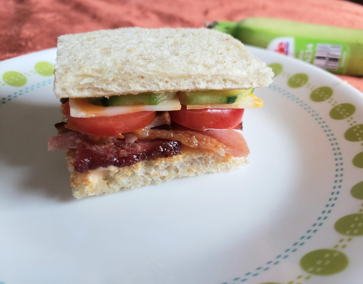 Little sandwich with bacon, cherry tomatoes, cucumber, cheese and spicy garlic mayo