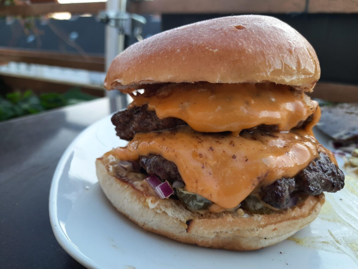 double cheese burger on the balcony, with onions, pickles and mustard