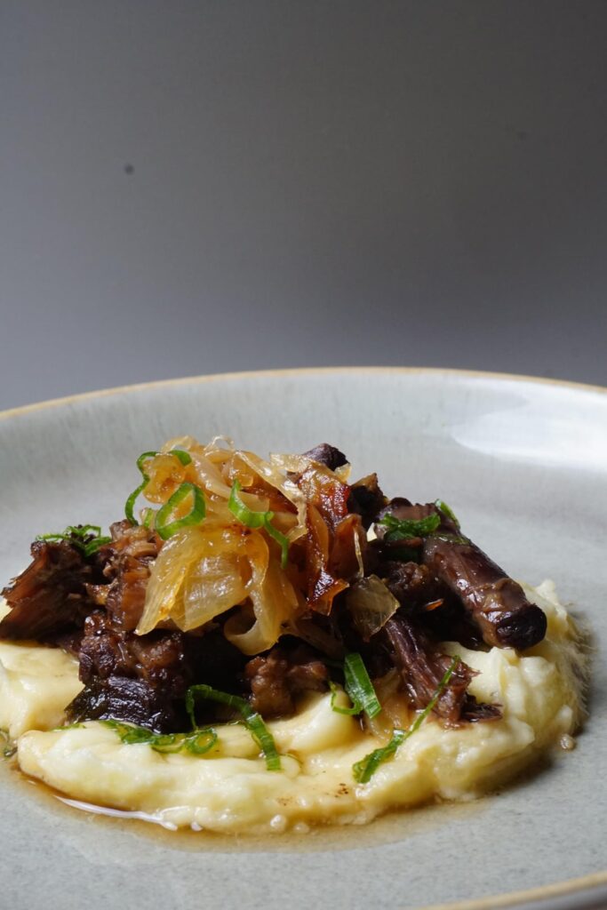 Garlic roasted pomme aligot, braised oxtail and caramelized onions.