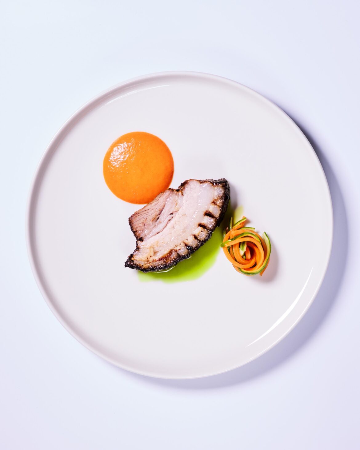 Slow roasted pork belly, chili foam, chive oil, fermented cucumber and carrot.