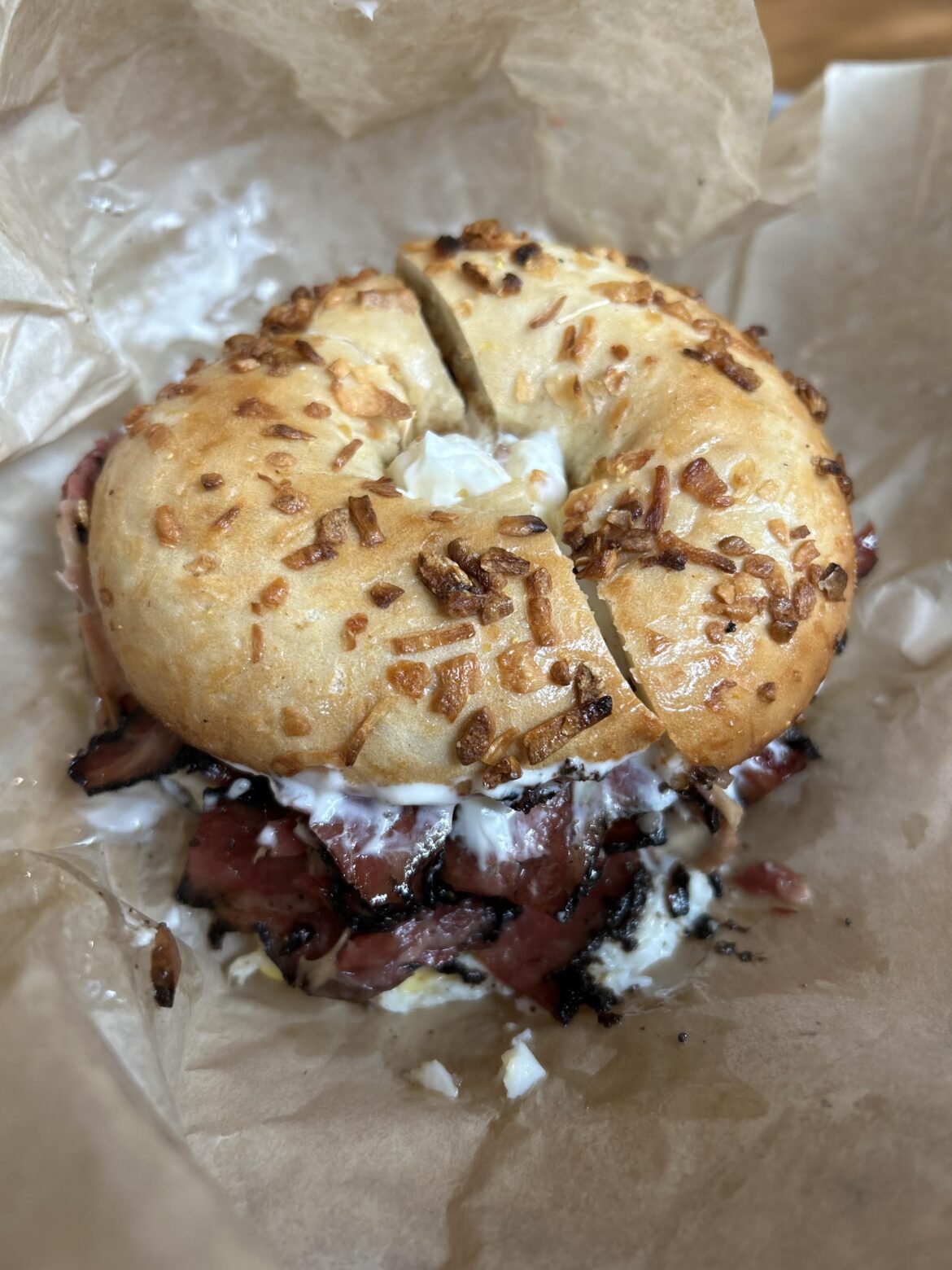 Onion bagel with cream cheese, pastrami and egg