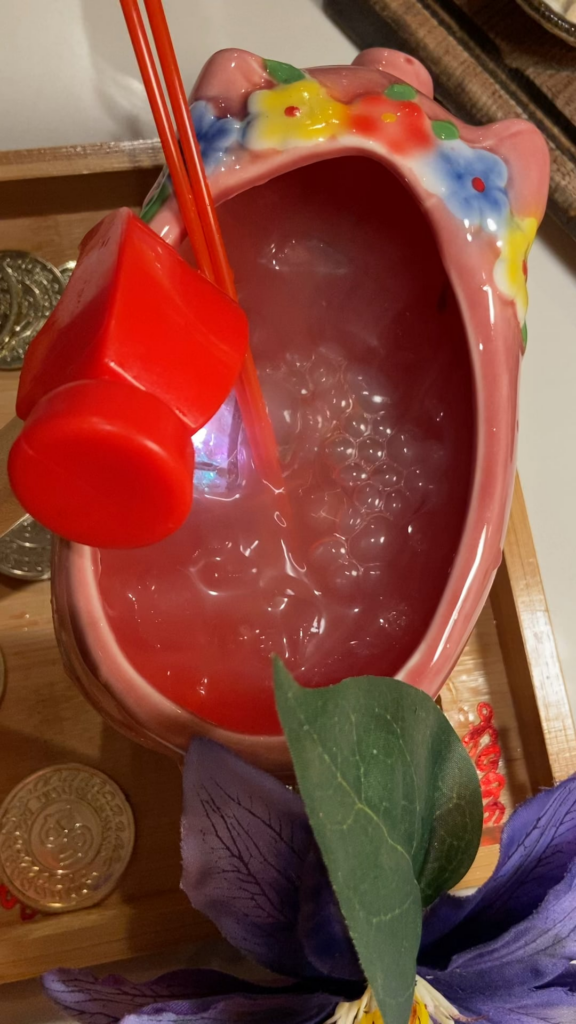 Drink in a pig plant pot (?) on a wooden tray with plastic gold coins and a mini hammer