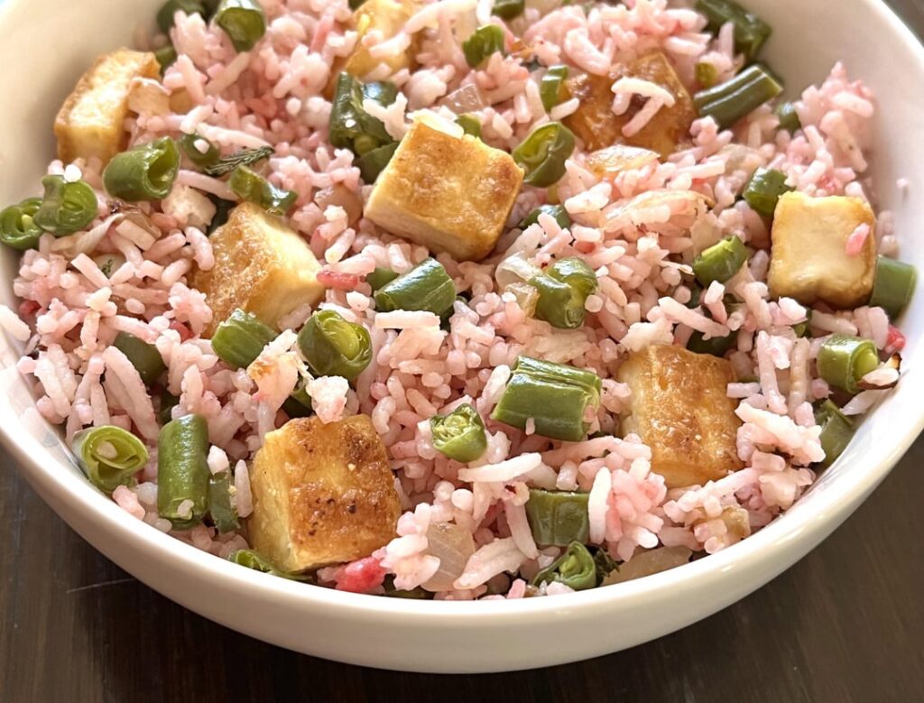 Pink jasmine rice with powdered beets, tofu and green beans. Sweet and spicy tomato-soy sauce at the bottom.