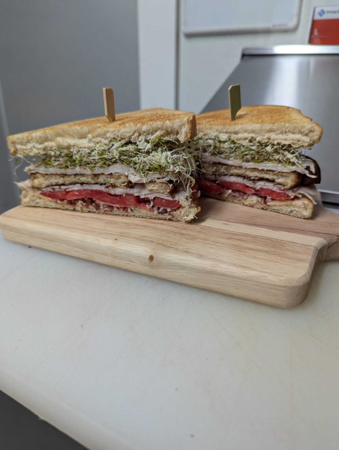 Turkey club special I made for my restaurant. OatNut bread, candied jalapeño cream cheese, alfalfa sprouts, heirloom tomato, smoked turkey breast, crispy prosciutto bits