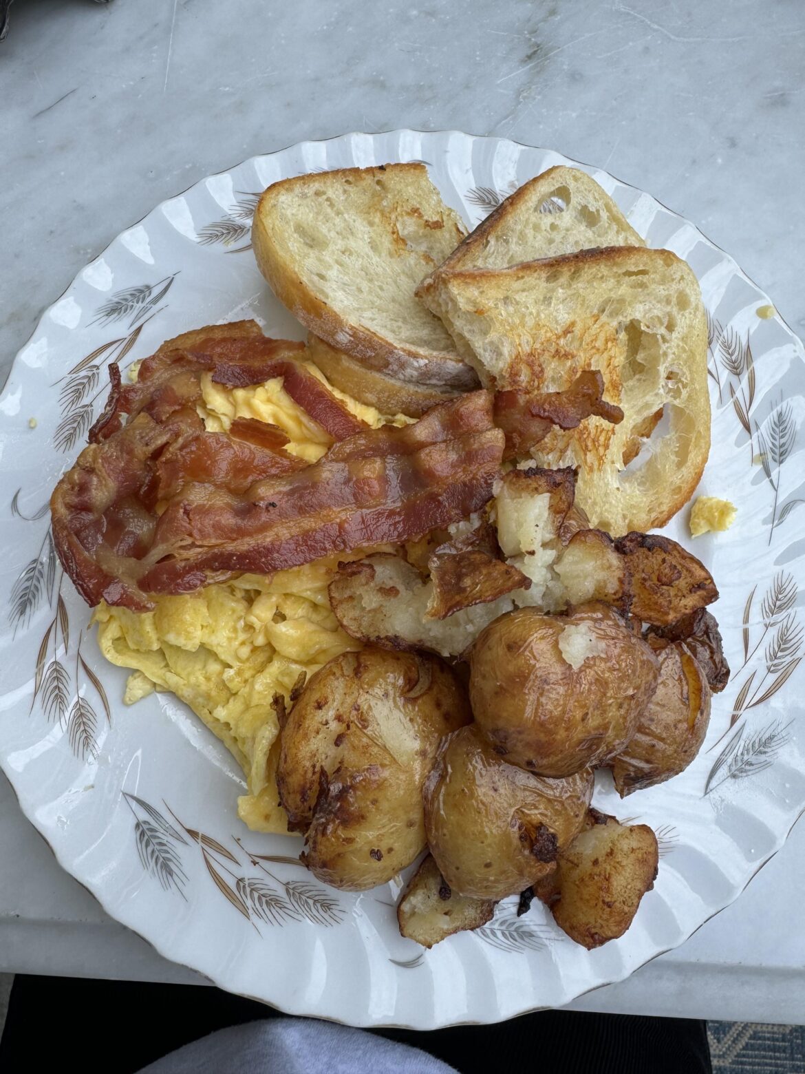 Scrambled eggs, bacon, potatoes and toast