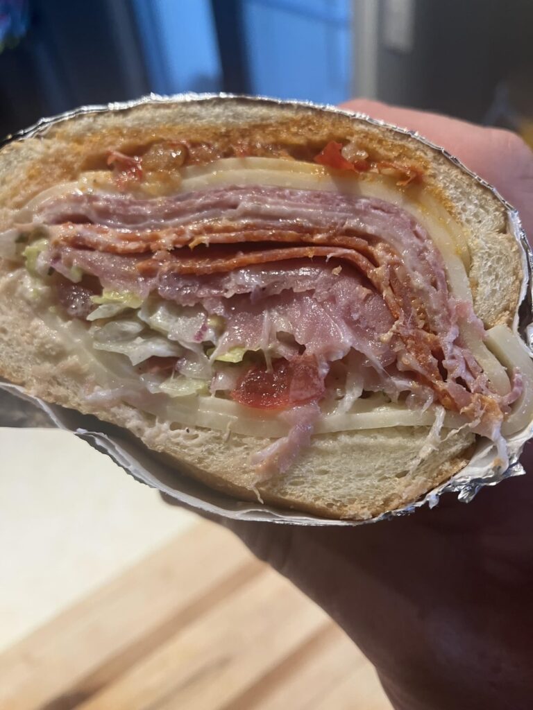Italian with provolone,salami, ham, pepperoni, prosciutto, banana peppers, Calabrian chili spread, mozz, and a salad of lettuce, tomato, onion,basil, oregano, mayo, red wine vinegar, salt and pepper.  Photos in reverse order.