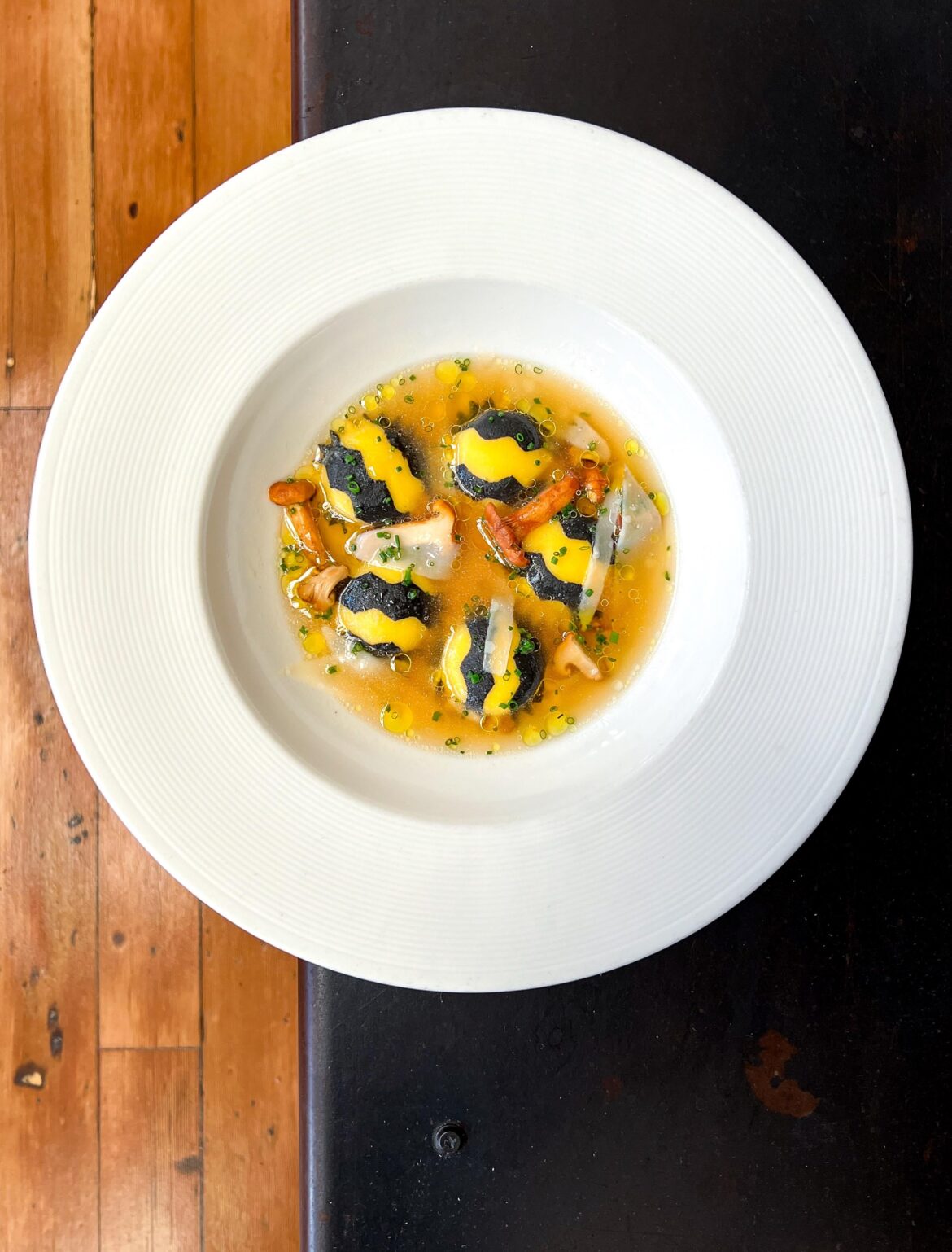 Ricotta + lobster filled squid ink pasta, lobster consommé, chanterelles, shaved pecorino
