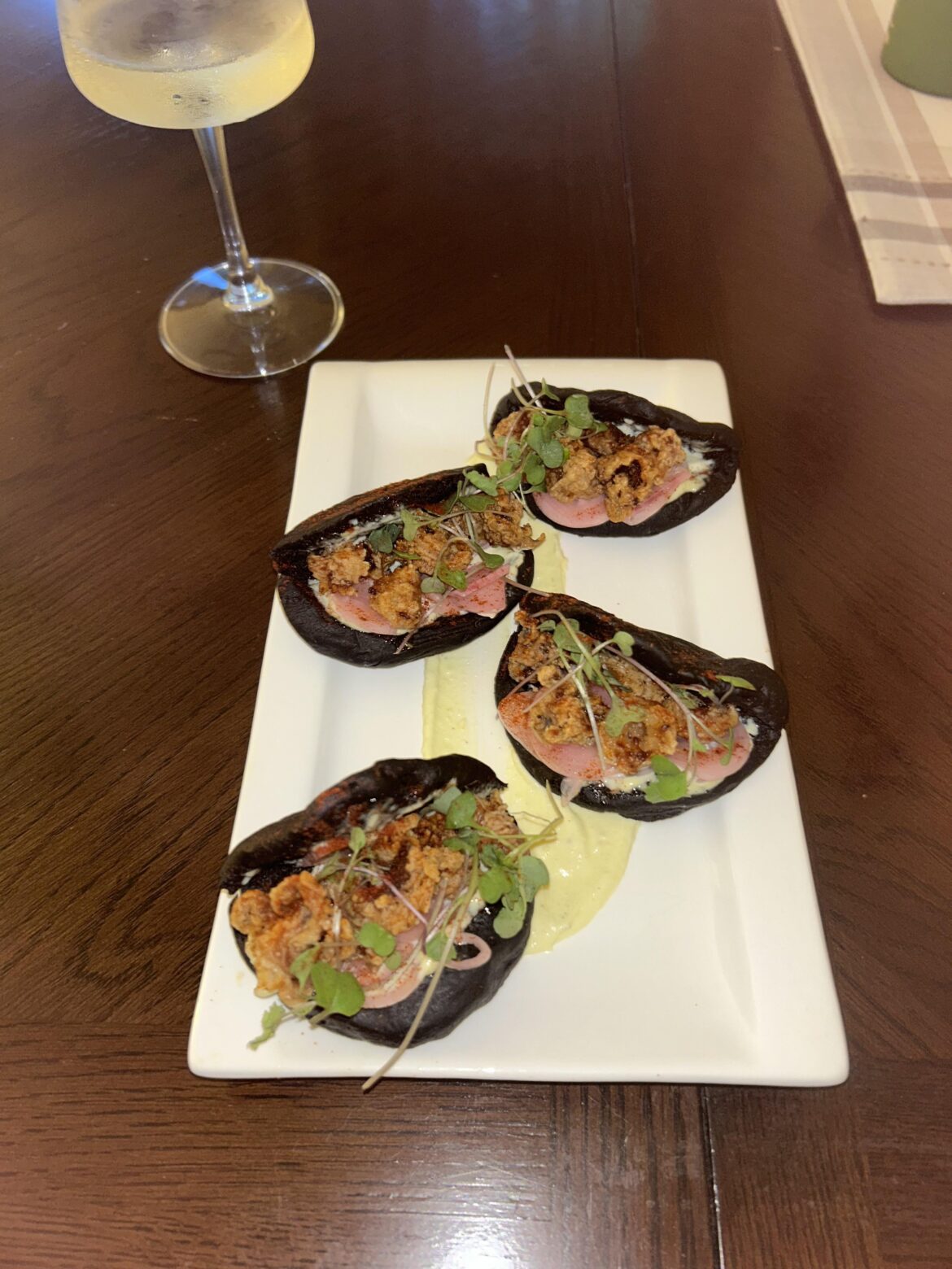 Squid ink bao, fried calamari, lemon wasabi aioli, pickled shallots, dusted with smoked paprika