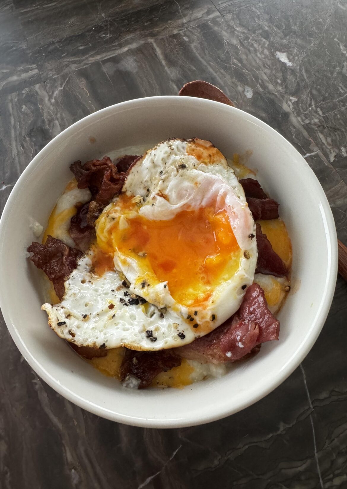Cheesy grits with beef bacon, topped with an egg
