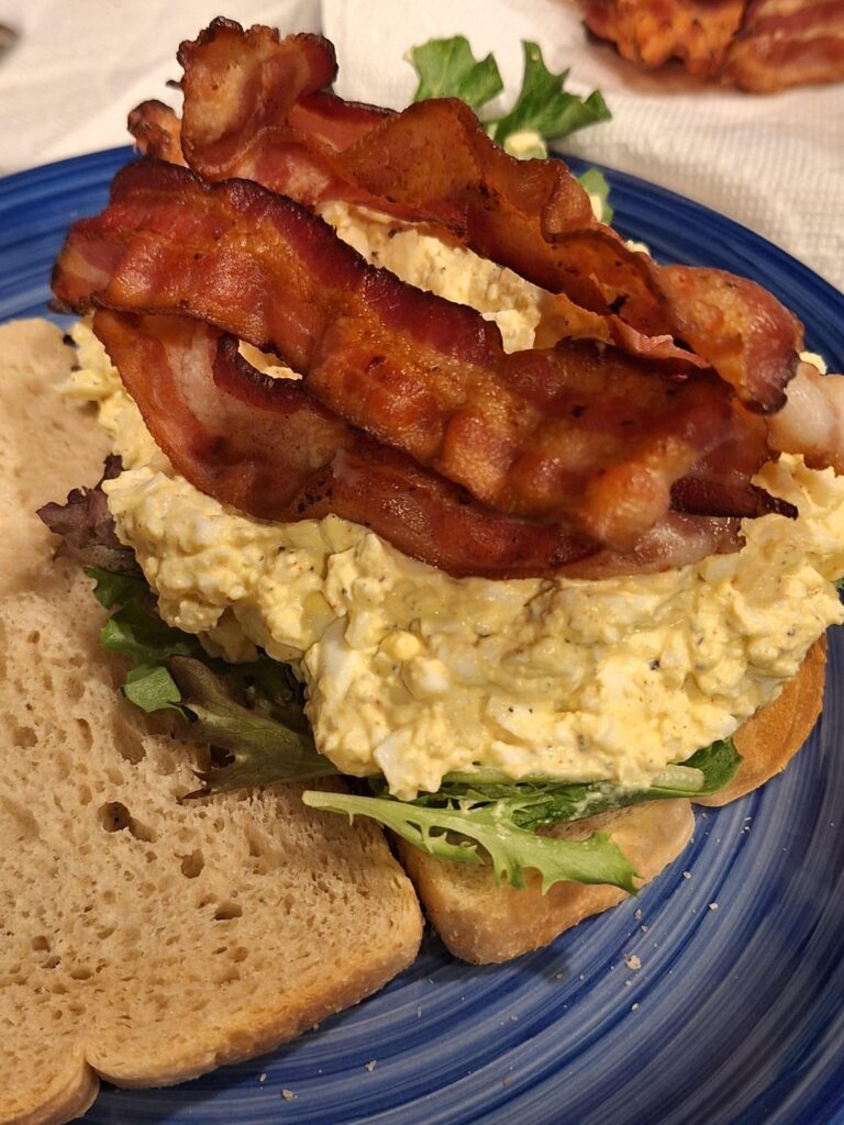 Egg salad sandwhich with crispy bacon on toasted sourdough.