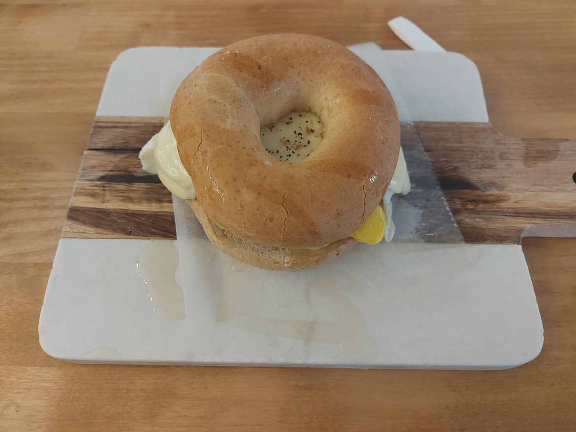 Bagel sandwich served on a half-marble, half-wooden cutting board, drizzled with oil? (Bridgeport, WV)