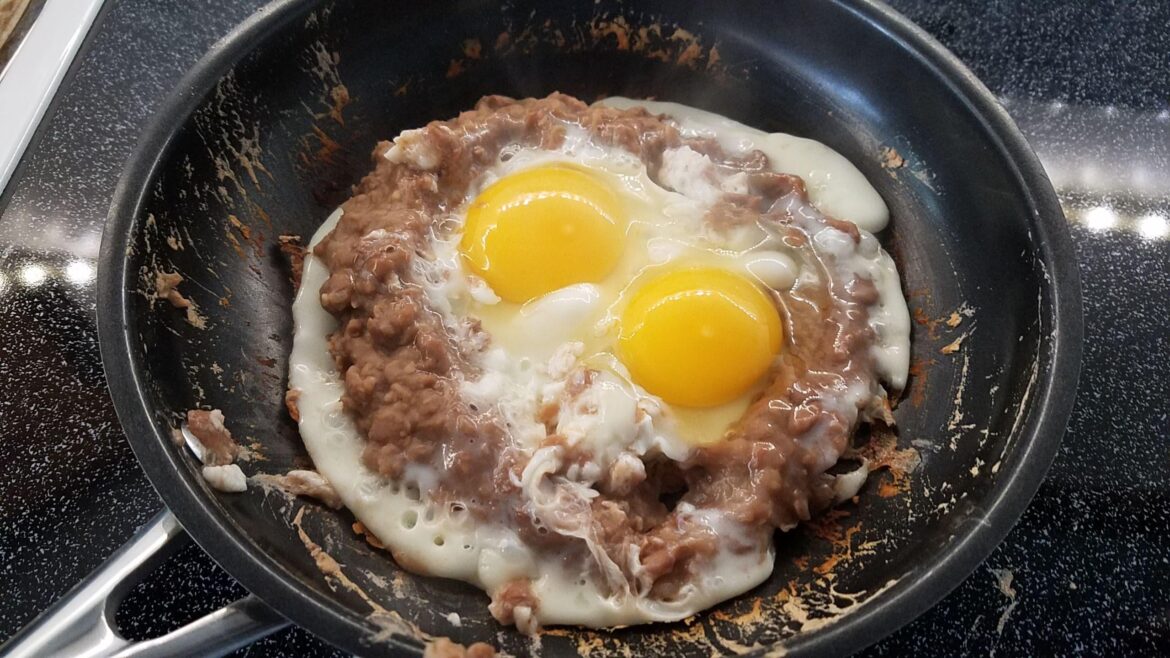 Two eggs simmering in a fortress of refried beans