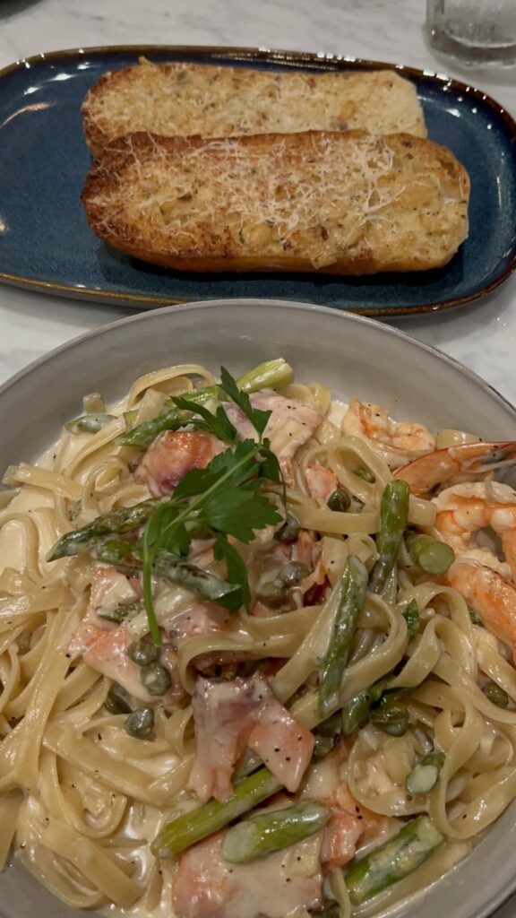 Seafood Pasta ; Shrimp, Smoked Salmon, M Capers, Asparagus, Cream Sauce and Fettuccine Noodles with a side of Cheesy Garlic Bread. (Bossa Nova Brazilian Cuisine)
