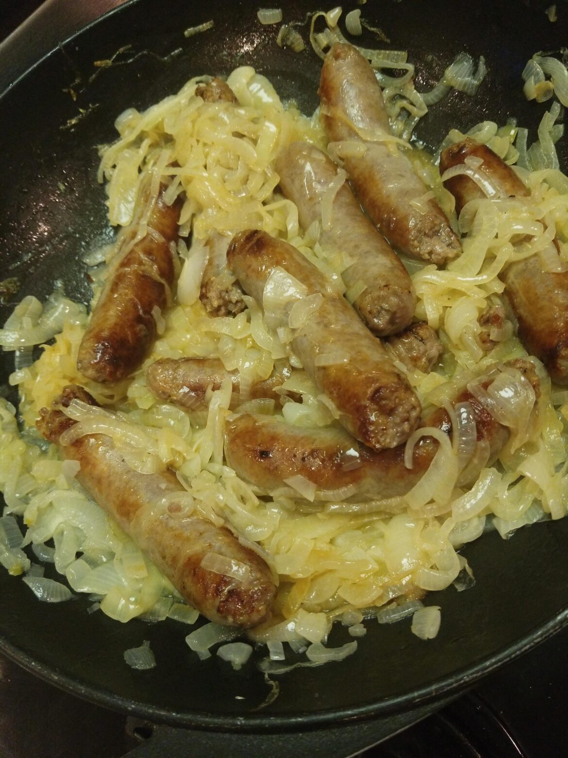 Grilled brats steaming in caramelized onions