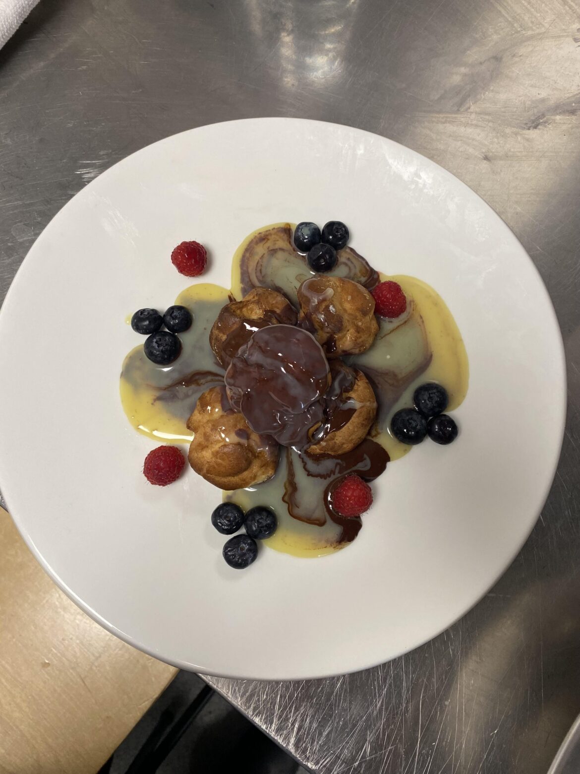 Choux Pastry filled with chantilly cream, garnished with fresh fruits, dark & white chocolate sauce