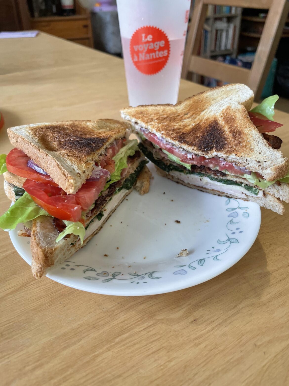 Club sandwich with deli sliced chicken breast, home grown kale on the bottom, BLT on top on toasted whole wheat sandwich bread