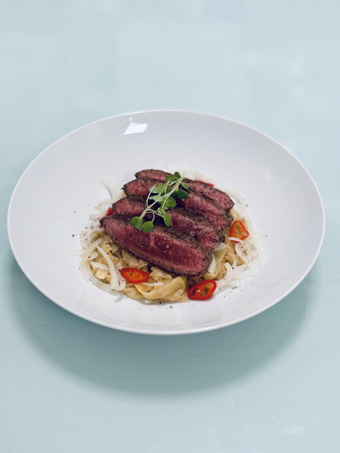 Iron steak, sweet garlic-soy sauce noodles, chili slices, onion, micro arugula.