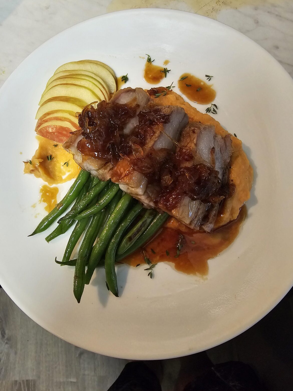 Pork Belly with caramelized onions, apple pomegranate gastrique, sautéed haricot vert, and sweet potato puree.
