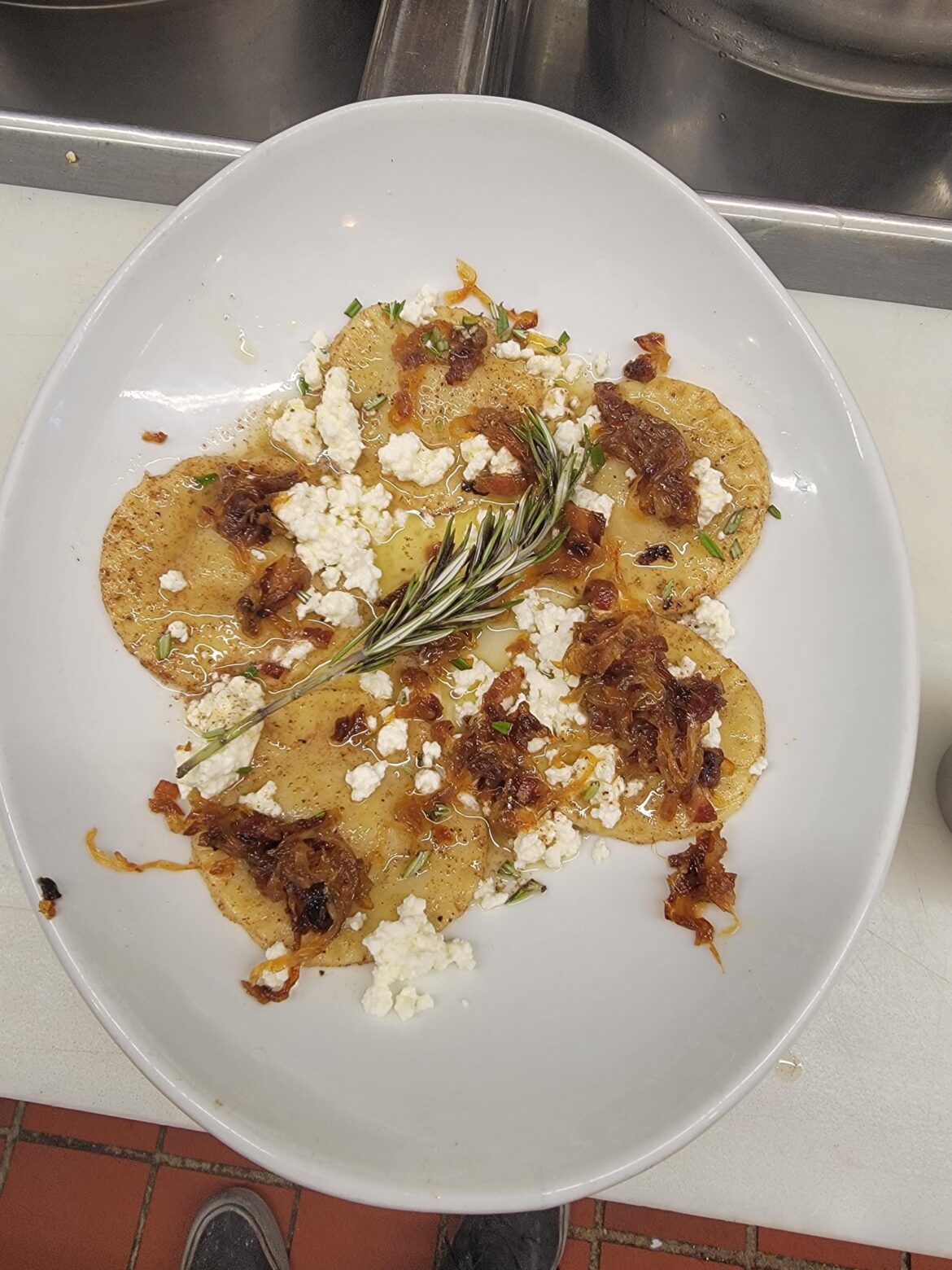 From scratch acorn squash ravioli, fresh ricotta, pork belly and onion marmalade, sprig of rosemary.
