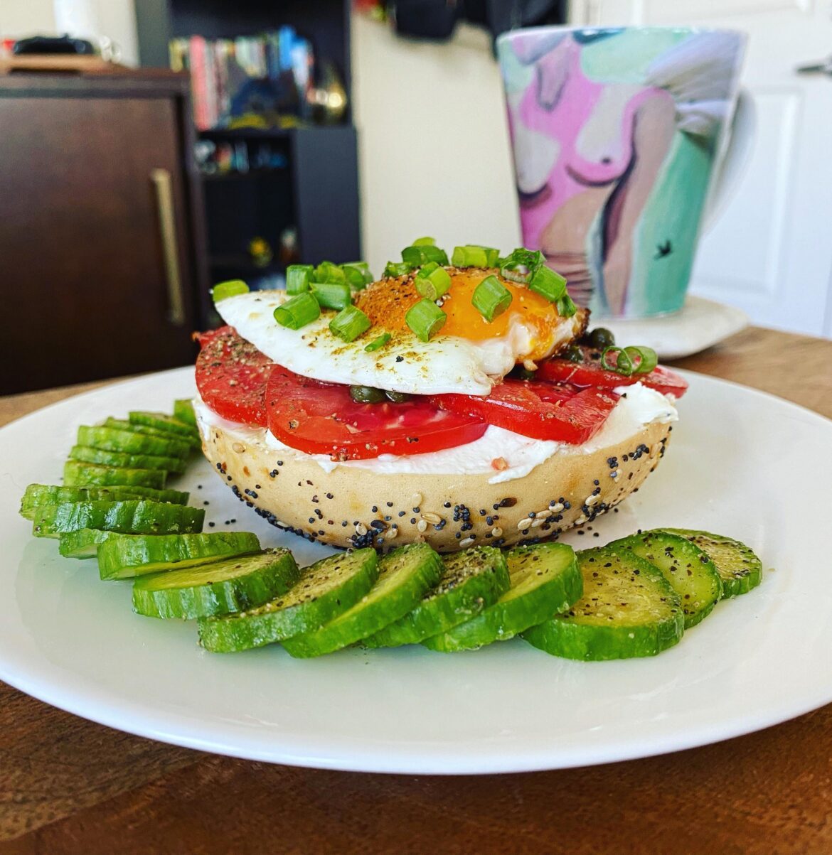 Egg, tomato, green onion, cream cheese, everything bagel, and sliced cucumber on the side