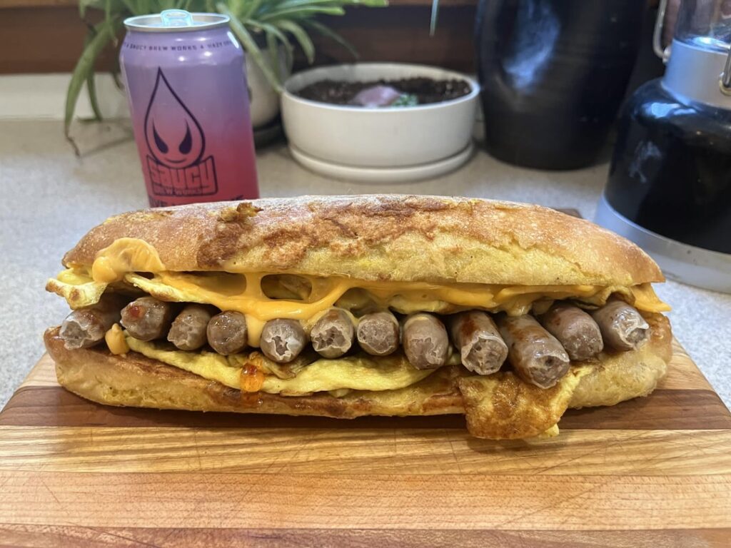 Scrambled egg, sausage, American, and bacon jelly on a French toasted baguette. Also, here’s how I eat these kaiju sandwiches. Wrap ‘em.