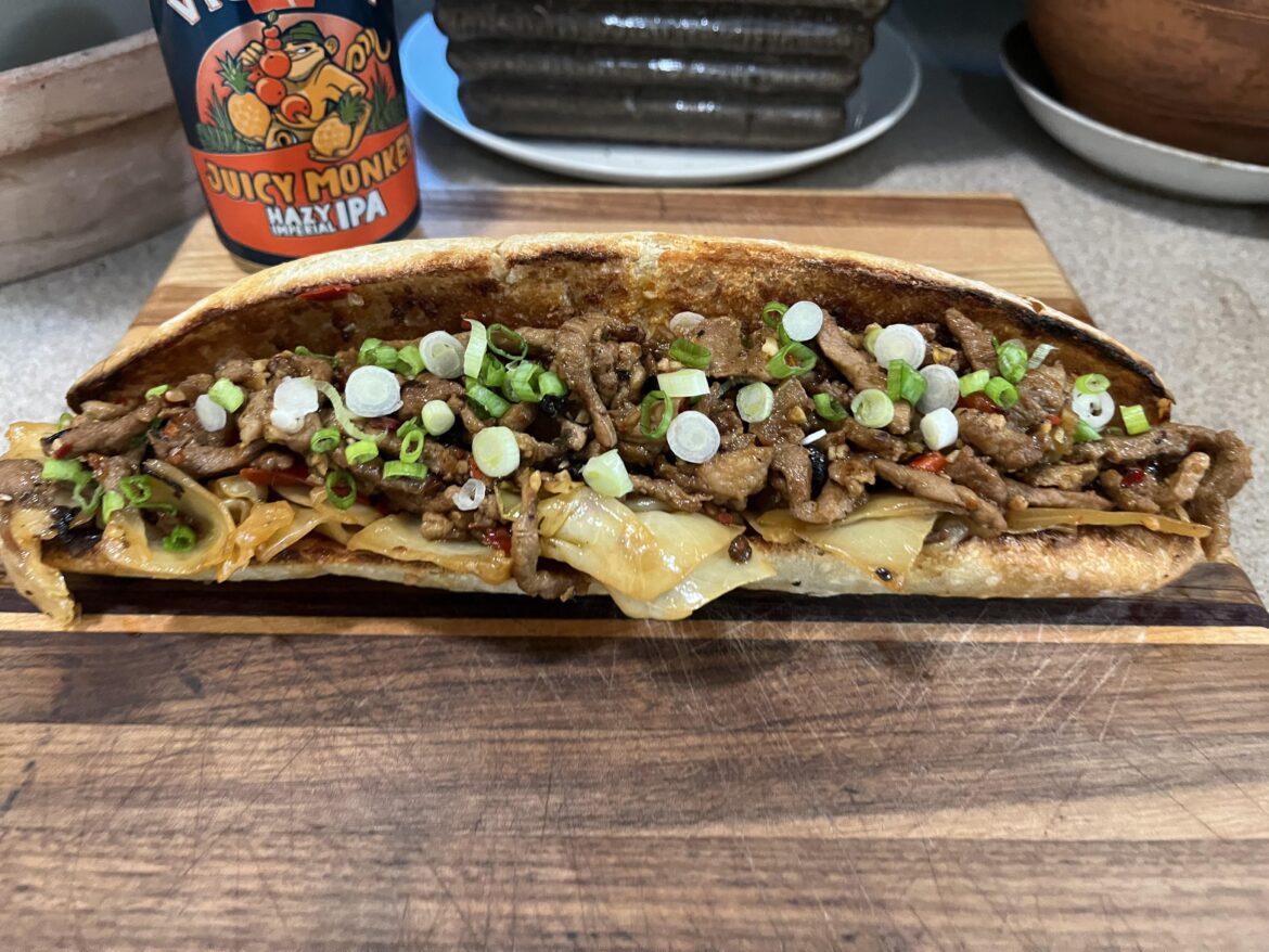 Sliced pork stir fried with cabbage and peppers in a spicy black bean sauce on a toasted baguette.