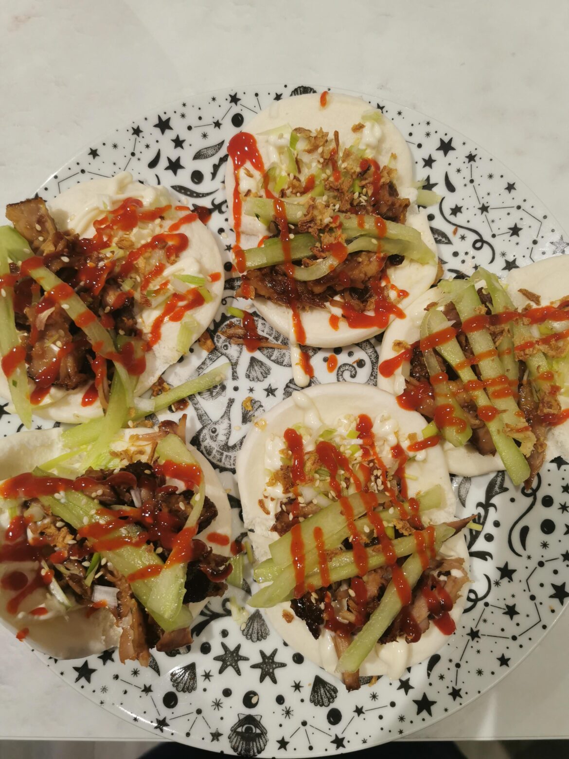 Miso glaze pork rib meat on steamed Bao with sesame, spring onion, crispy onion, cucumber, Sriracha and Mayo.