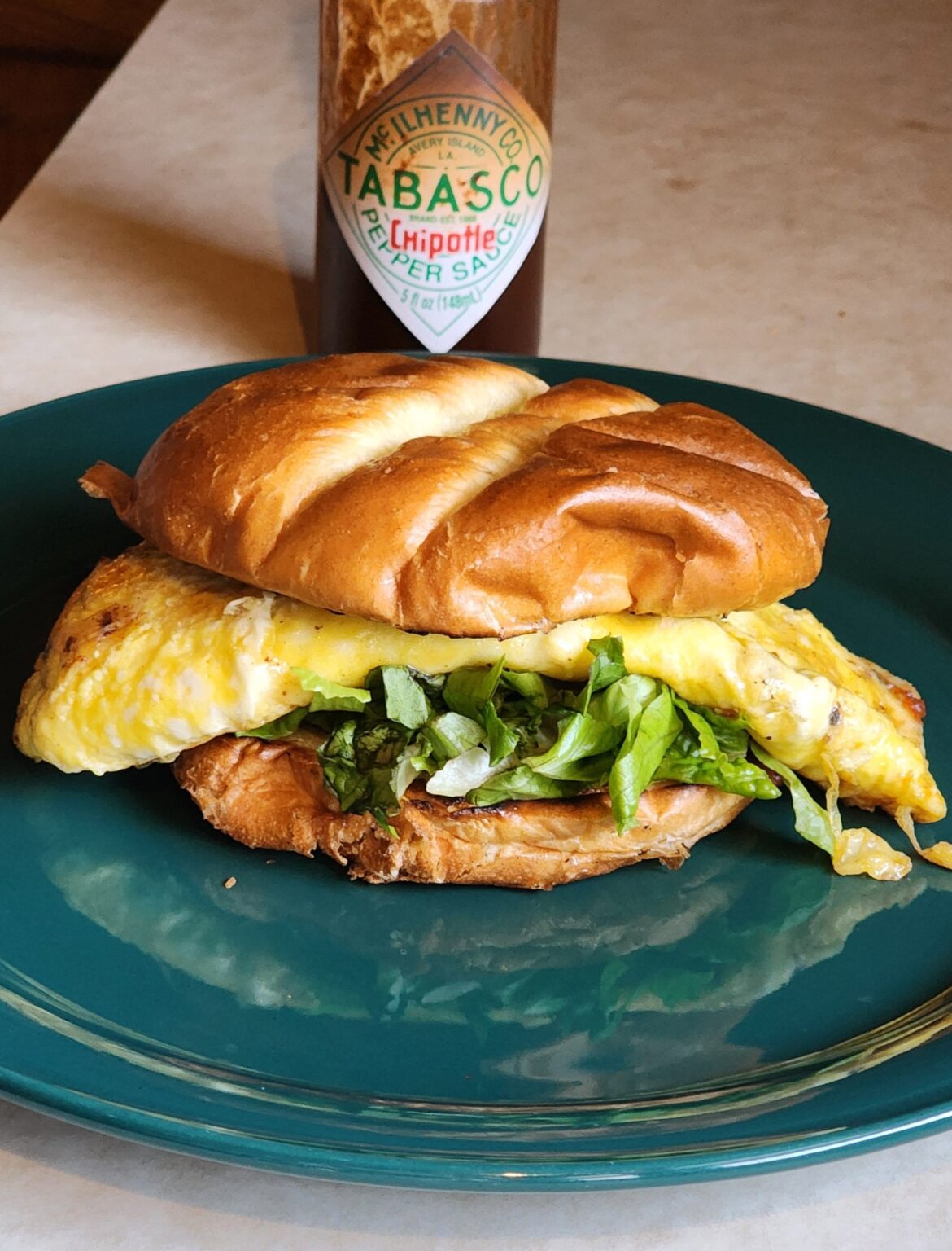 Omelet sandwich I just made. 2 eggs with jalapeño muenster cheese, carolina reaper cheese, chives, lettuce, smoked tobasco.