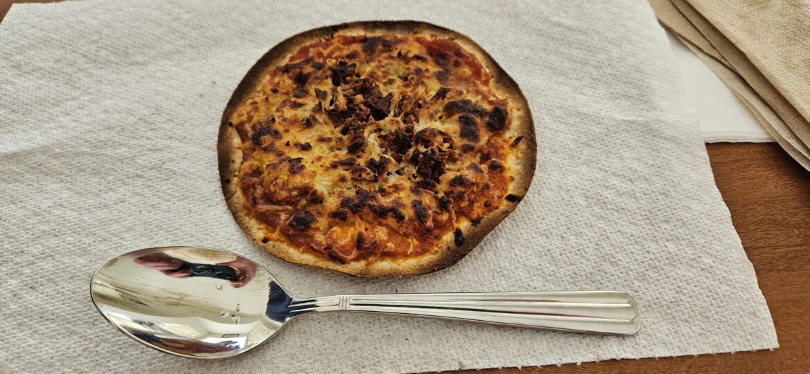 I call it bachelor pizza. Corn tortilla, spaghetti sauce, bacon bits (optional), and Italian cheese, in the toaster oven. Dessert spoon for scale.