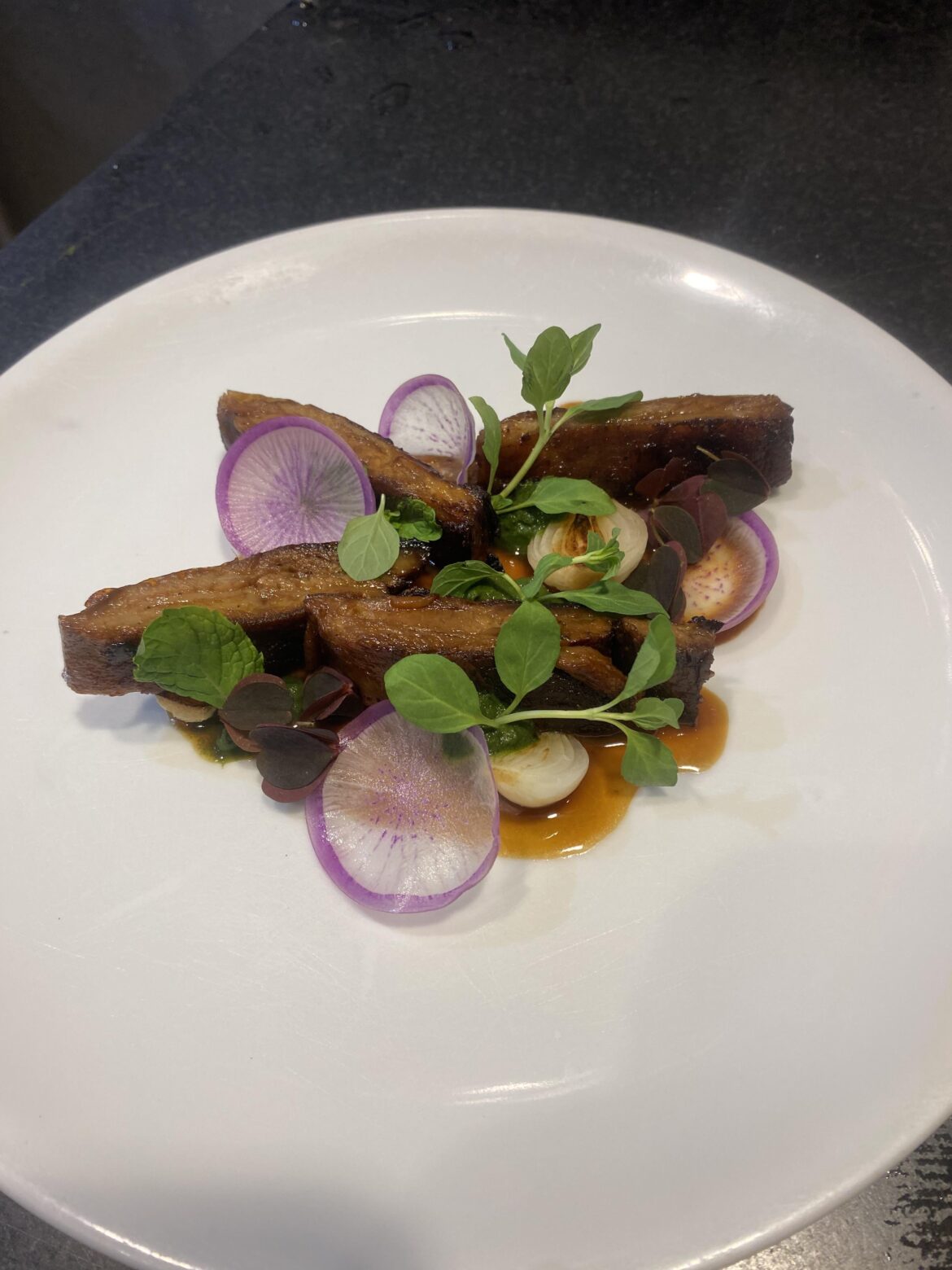 Lamb rack “bacon” braised, pressed and seared, roasted spring onions, mint pistou, micro mint and pea tendrils.