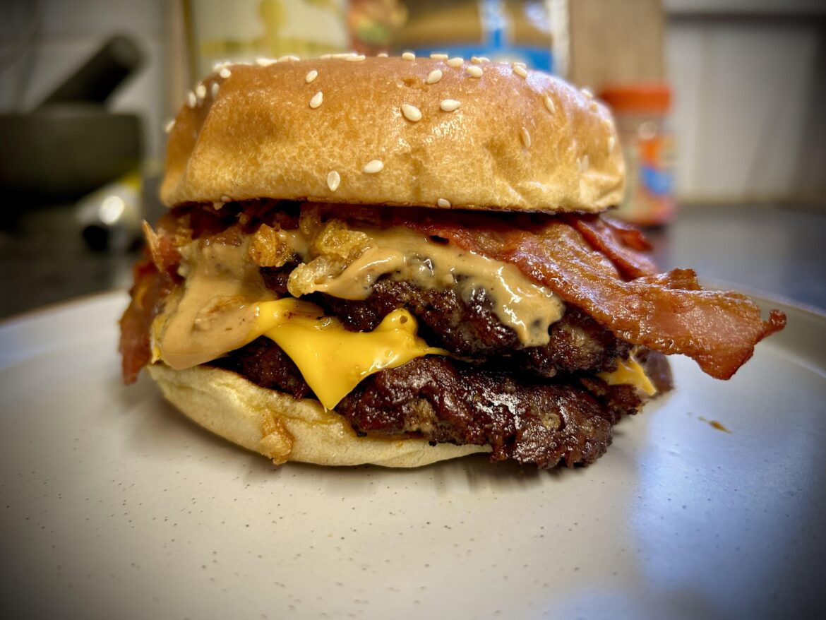 Homemade double smash burger in toasted brioche with cheese, bacon, bbq sauce, crispy onion and peanut butter.