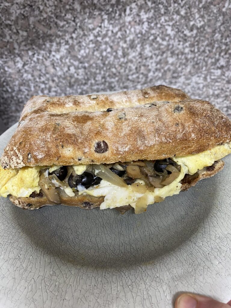 Omelette with onions, mushroom, black olives and Swiss cheese on an olive fougasse loaf