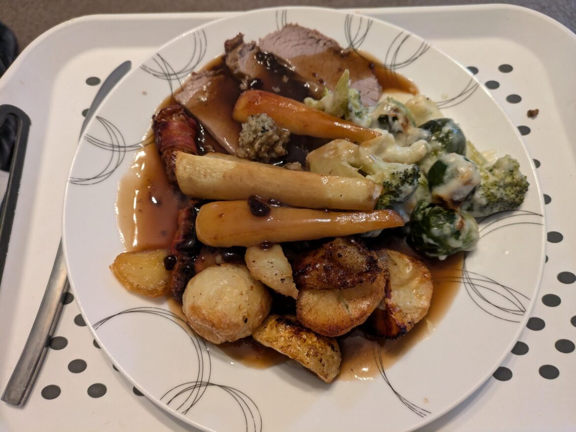Roast Beef dinner with honey roast parsnips a couple of pigs in blankets and a broccoli and Brussel sprouts cheese bake