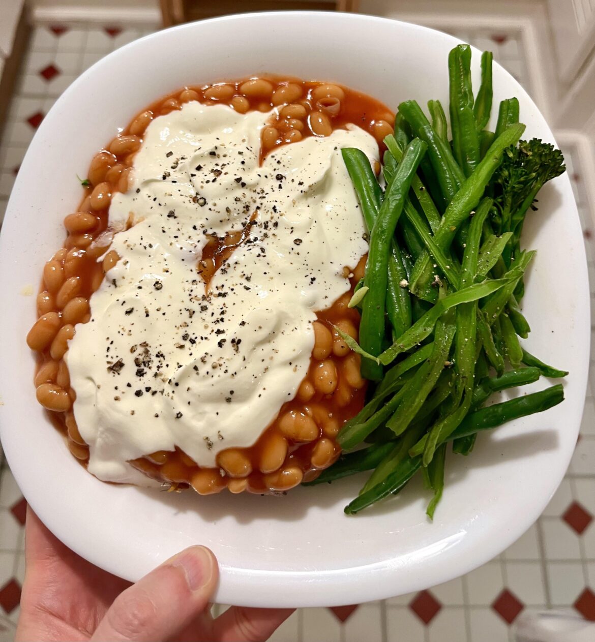 Roasted sweet potato buried under beans and soured cream, with green beans and broccoli
