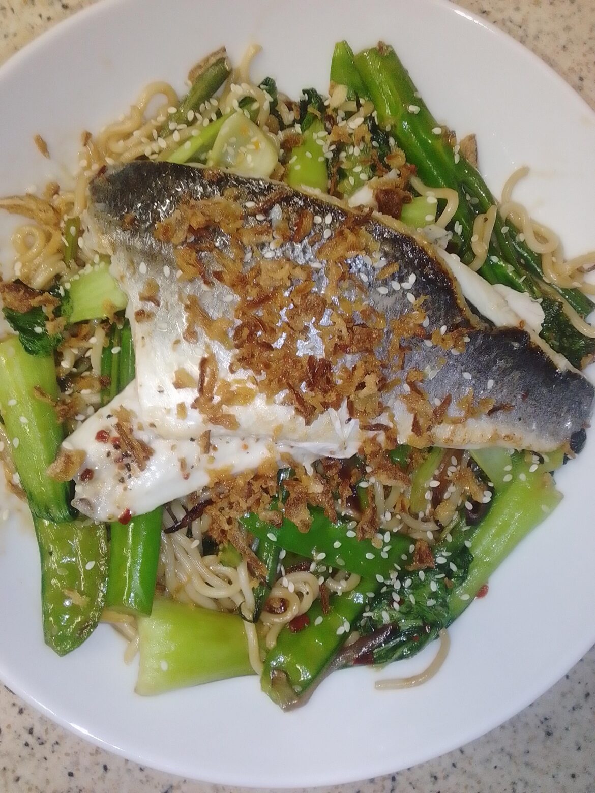 Sea bass, stir fried vegetables & noodles. Crispy onions.