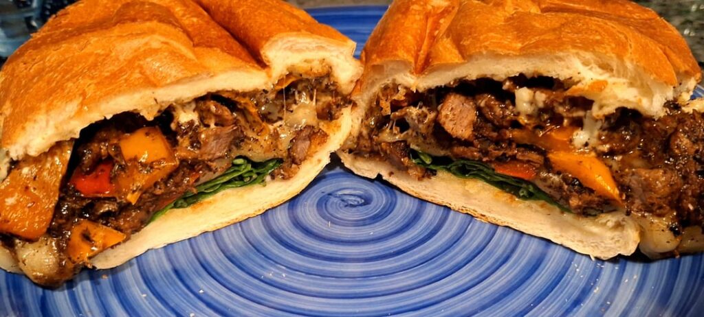 Beef round strips sandwhich with bell peppers, smoked provolone, spinach and Duke's mayo on French bread.