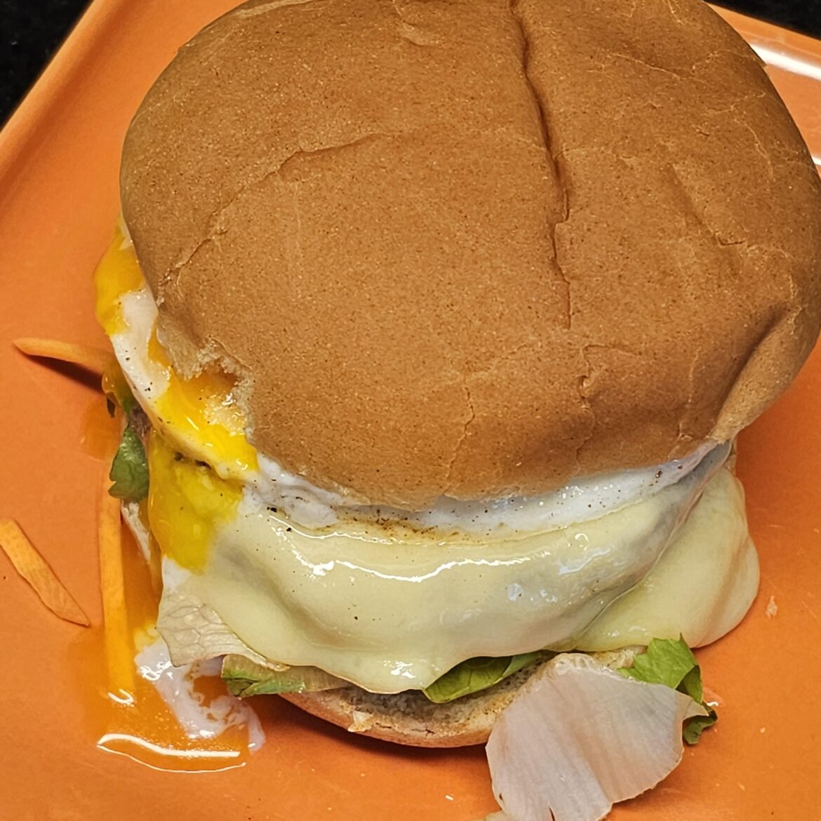 Burger with mixed salad, beef patty, burger sauce, freshly molten raclette cheese, and an egg on it