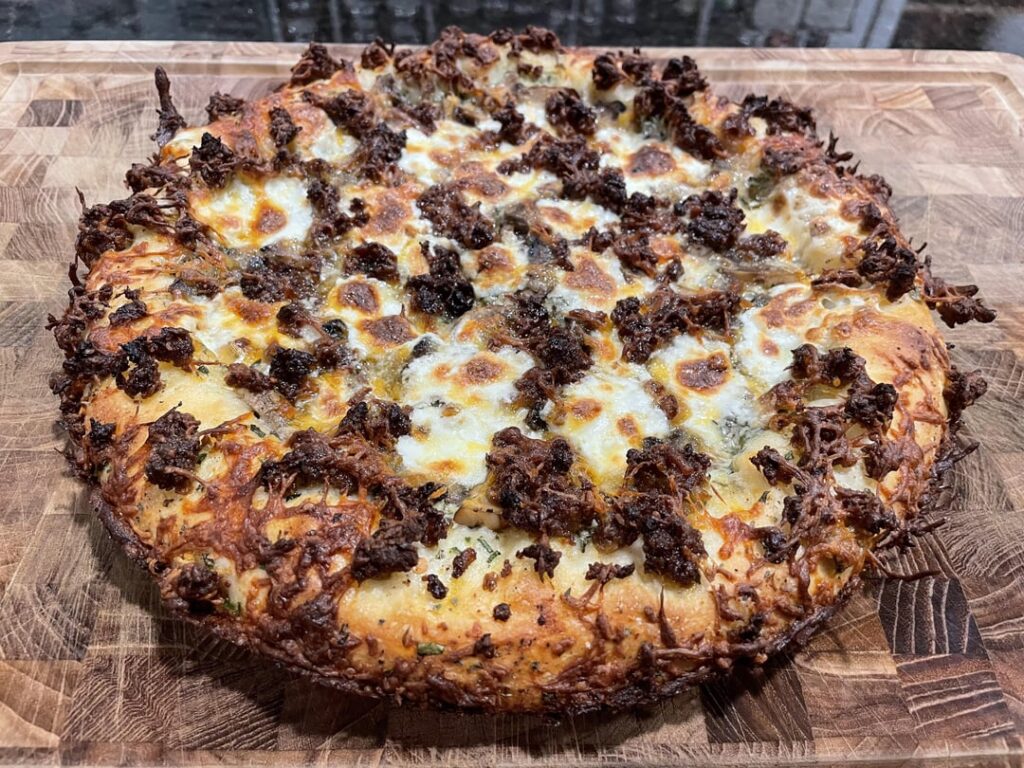Cast iron style stuffed crust pizza with spinach and artichoke dip, mushrooms, and Italian sausage.
