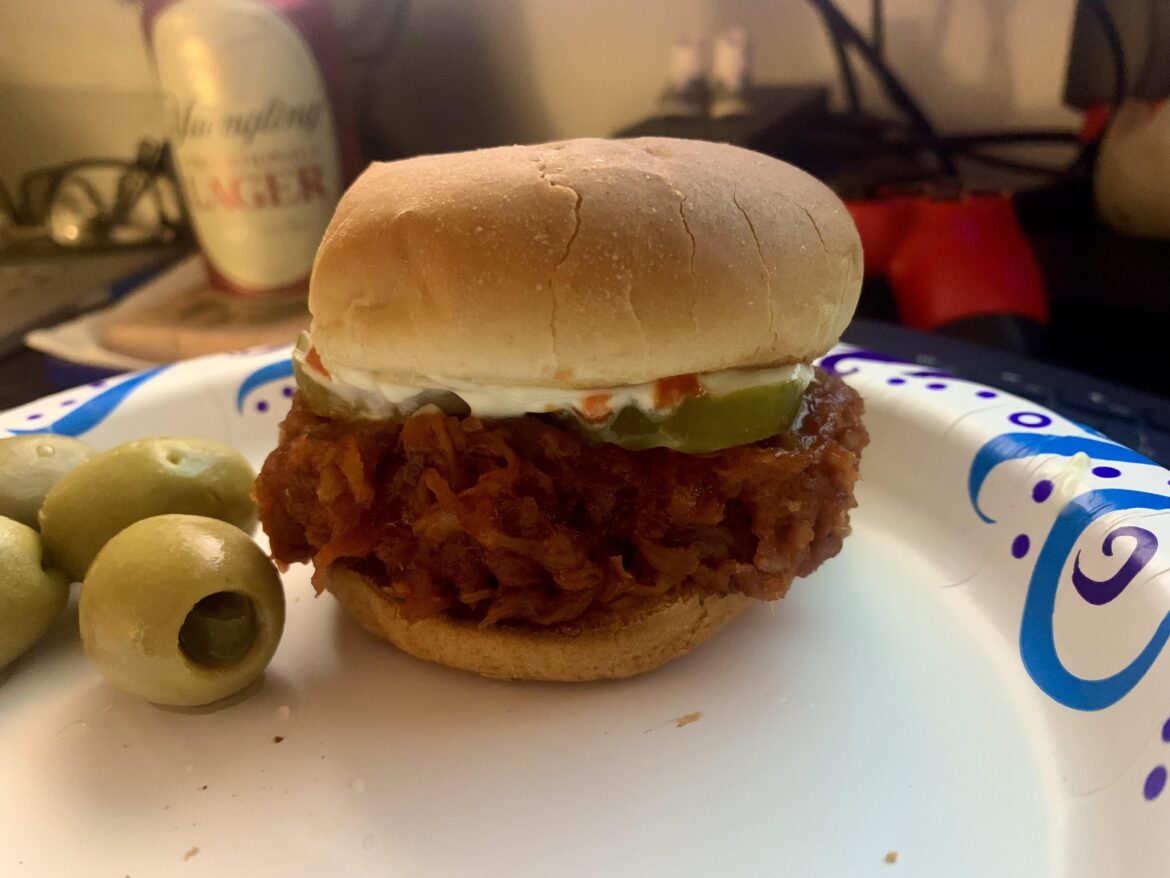 bbq pulled pork sandwich with some jalapeno stuffed olives on the side..