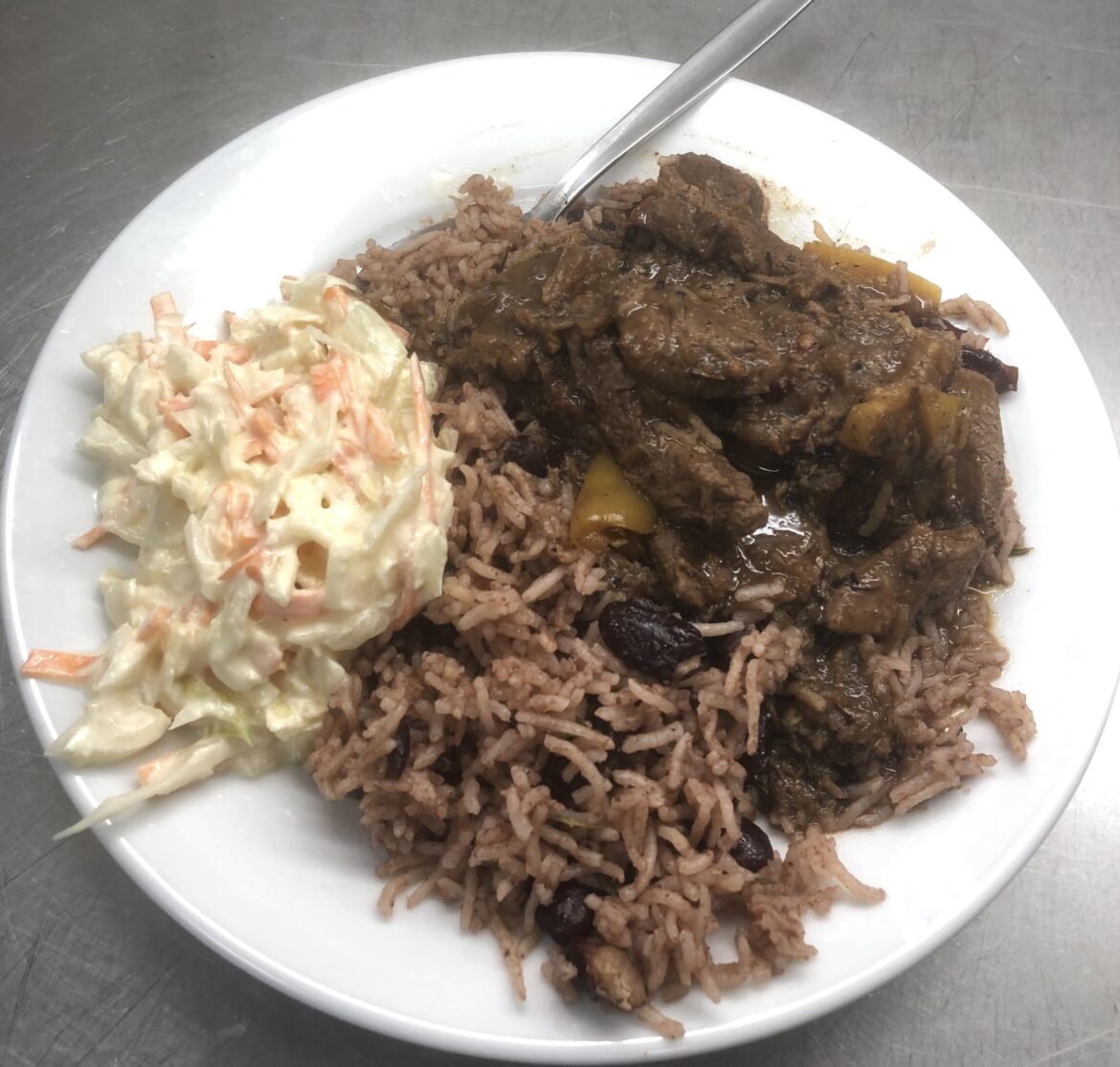 Stew lamb, rice and peas with coleslaw .