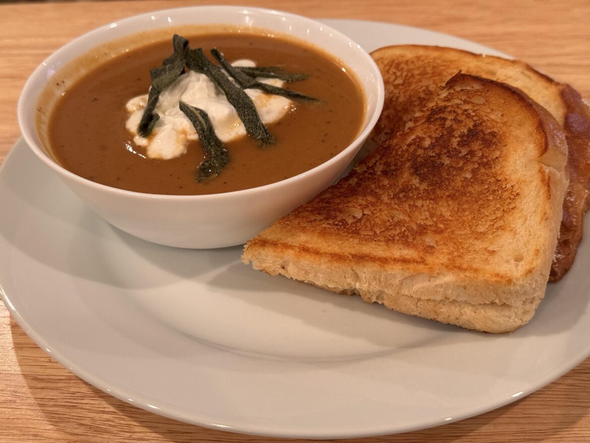 Sourdough and mozzarella grilled cheese with acorn squash soup, spiced whipped cream, and frizzled sage