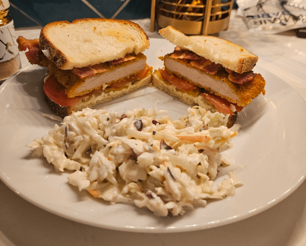 Pork cutlet sandwich with bacon, tomato, pickles, mayo, and a side of fresh cole slaw