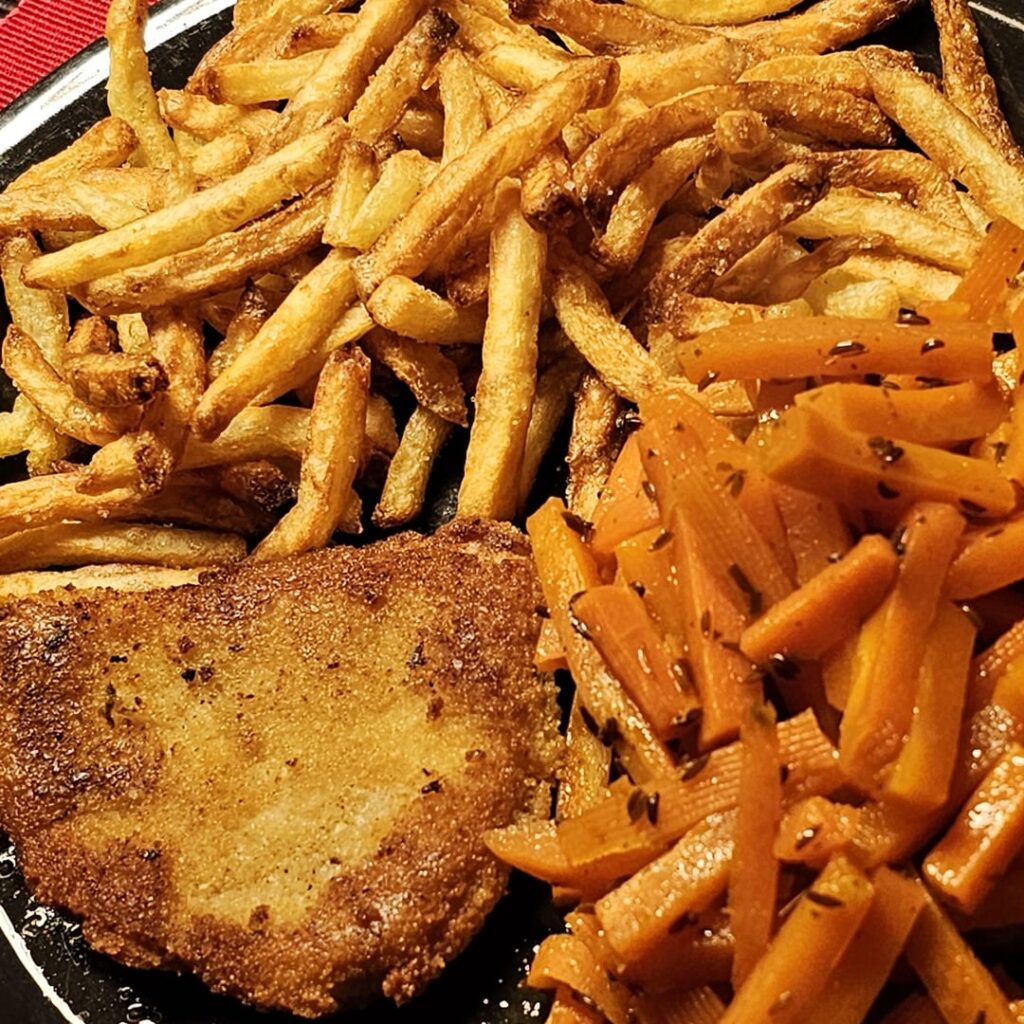 Breaded schnitzel with homemade fries and cumin-seasoned carrots
