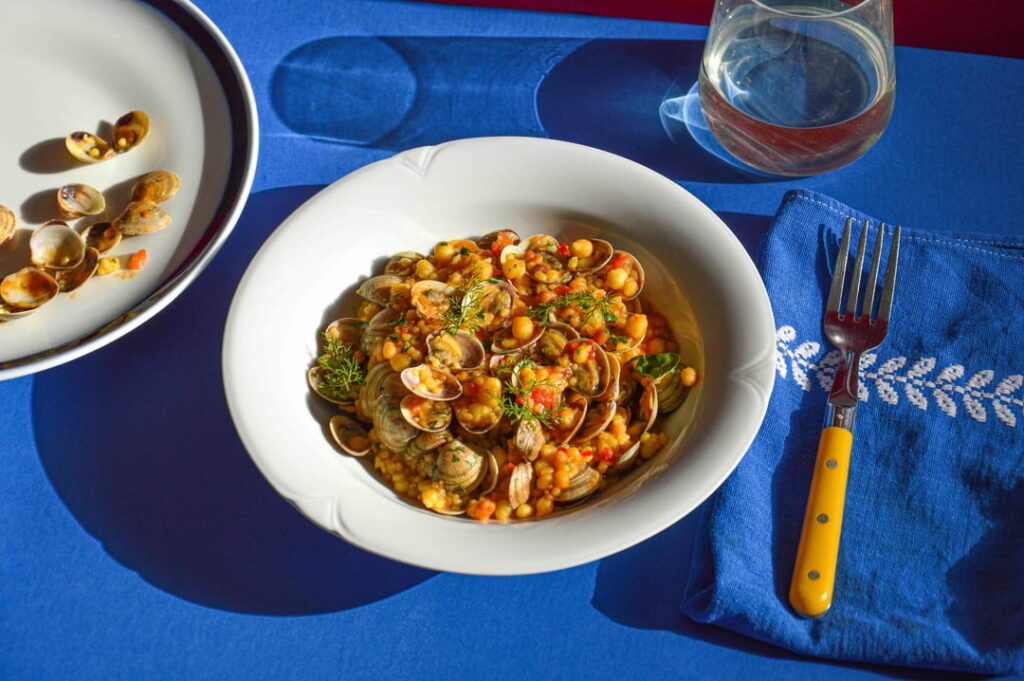 Fregula, hand-made Sardinian pasta served with clams in a saffron and tomato sauce