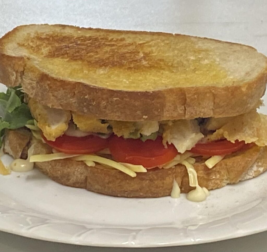 Crispy crumbed chicken, vintage cheddar, Roma tomato, garlic aioli, white pepper, home grown spring onion and butter lettuce on buttered pan fried ciabatta