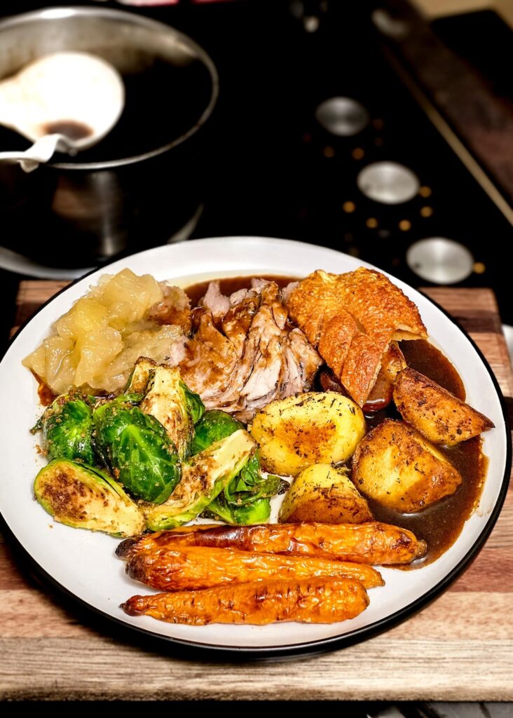 Roast pork with crackling, triple cooked potatoes, honey grilled baby carrots, brown butter sprouts, stewed apple, and pan dripping gravy.