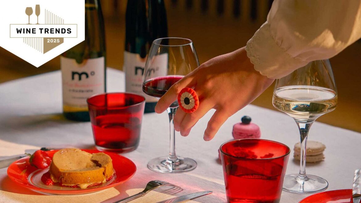 A photo of a hand picking up a glass of red wine