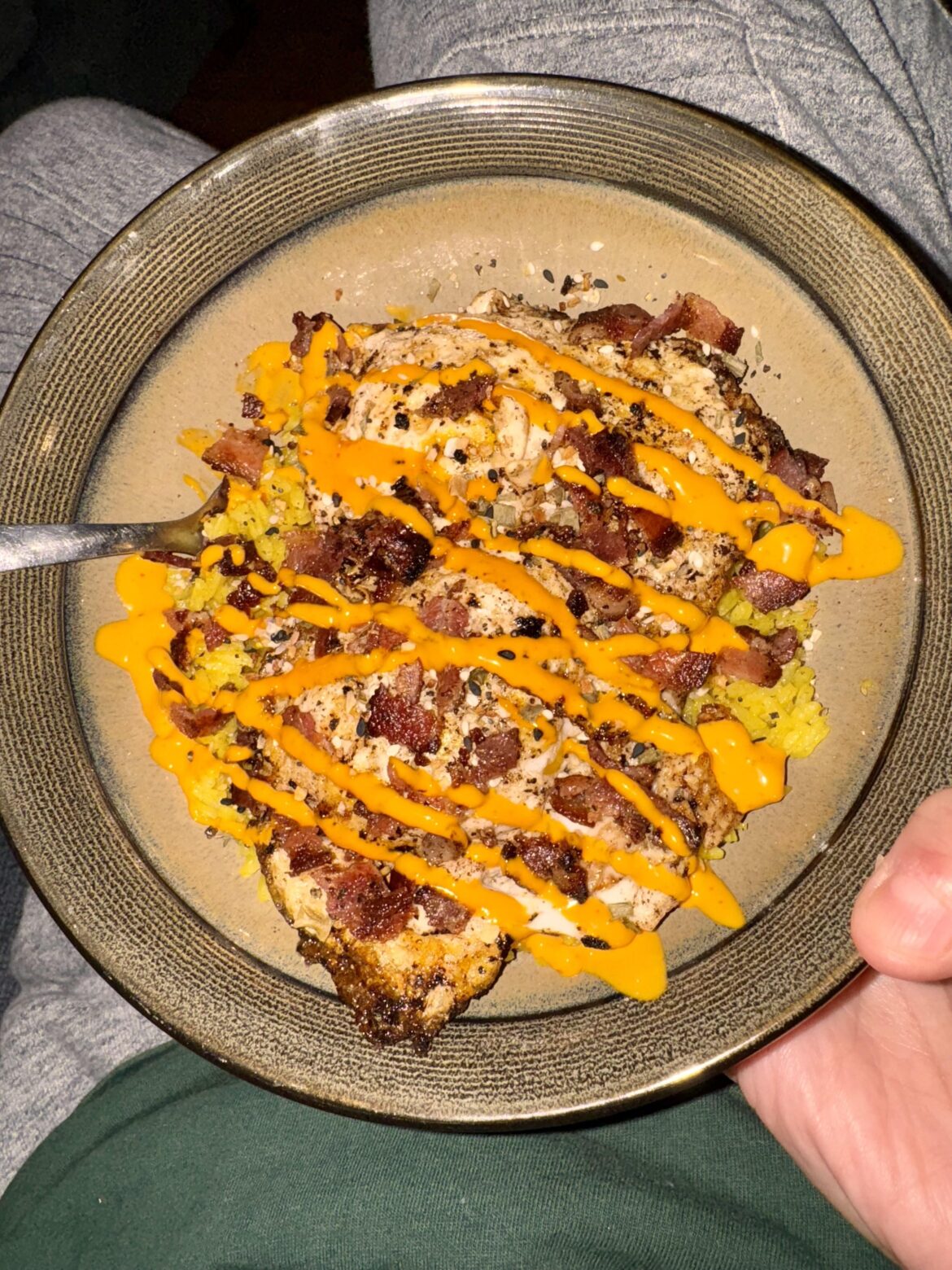 Yellow rice, fried egg, peppered bacon, sesame seeds, sriracha mayo