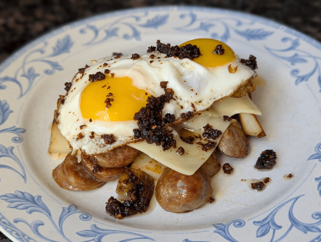 Sunnyside eggs over sausage home fried potatoes cheese, a drizzle of chili crisp
