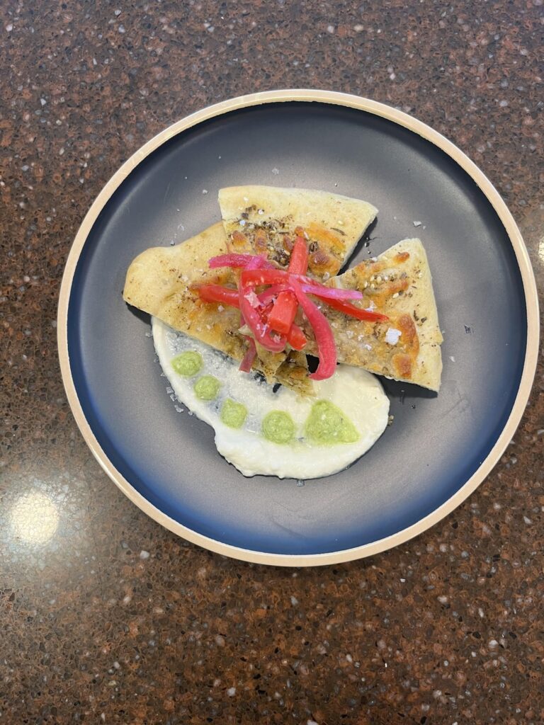 Manakeesh with whipped yogurt spread, tatbeeleh and pickled vegetables